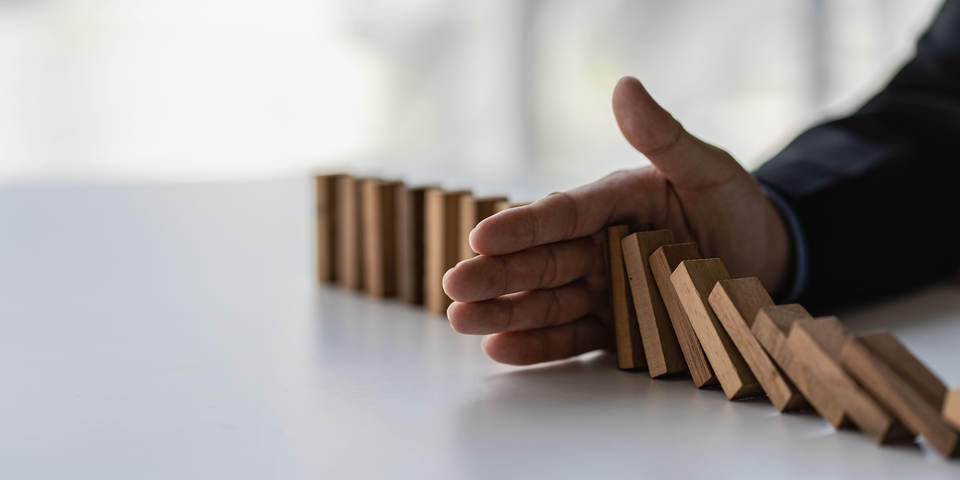 hand som stoppar fallande dominobrickor